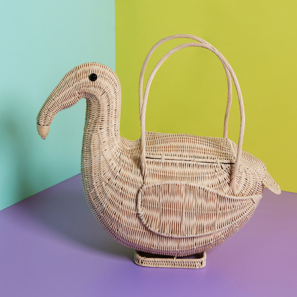 Wicker Darling DIY flamingo basket bird shaped-bag sits in a colourful background