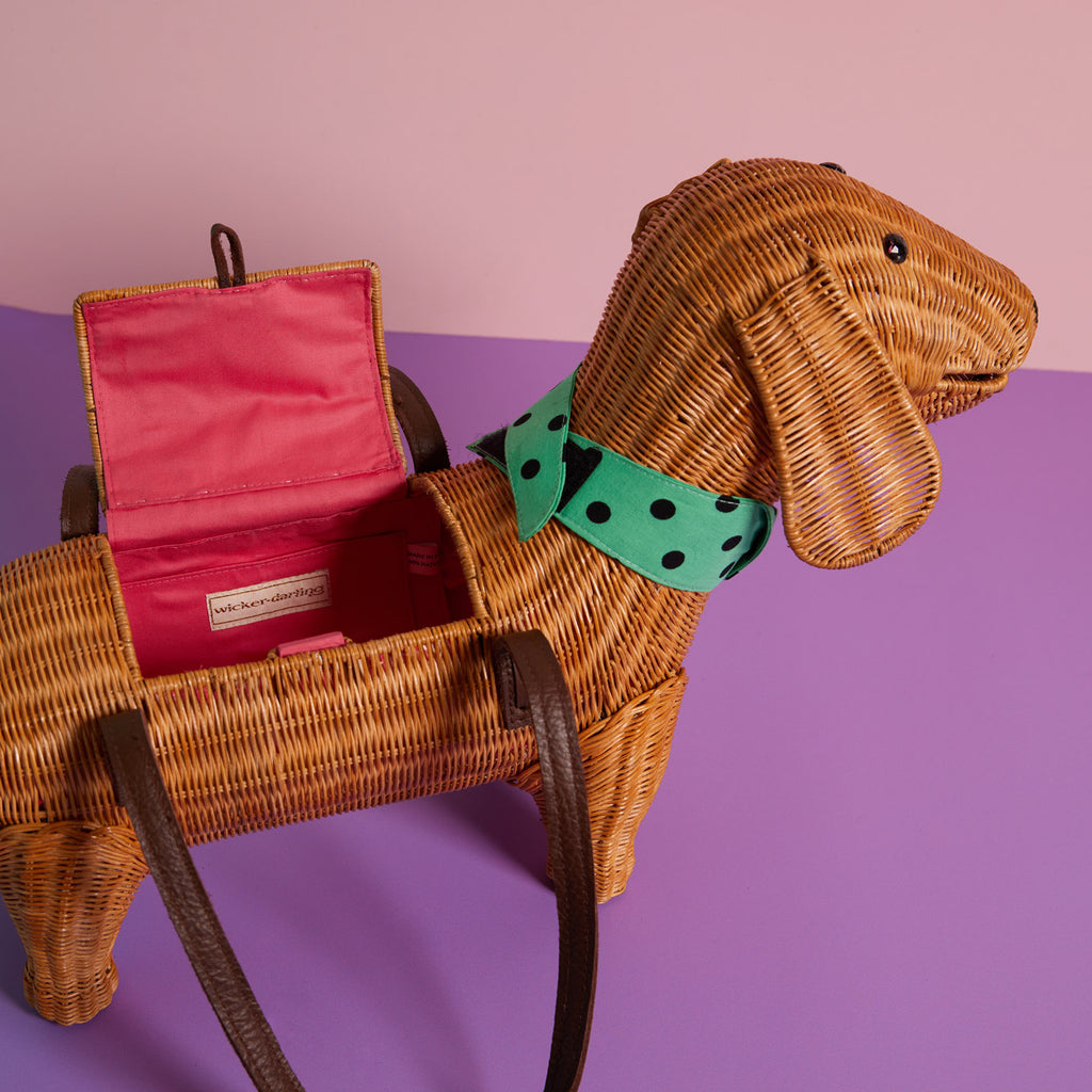 Andouille Sausage dog purse Dachshund handbag wears a blue bow-tie and sits in a colourful background