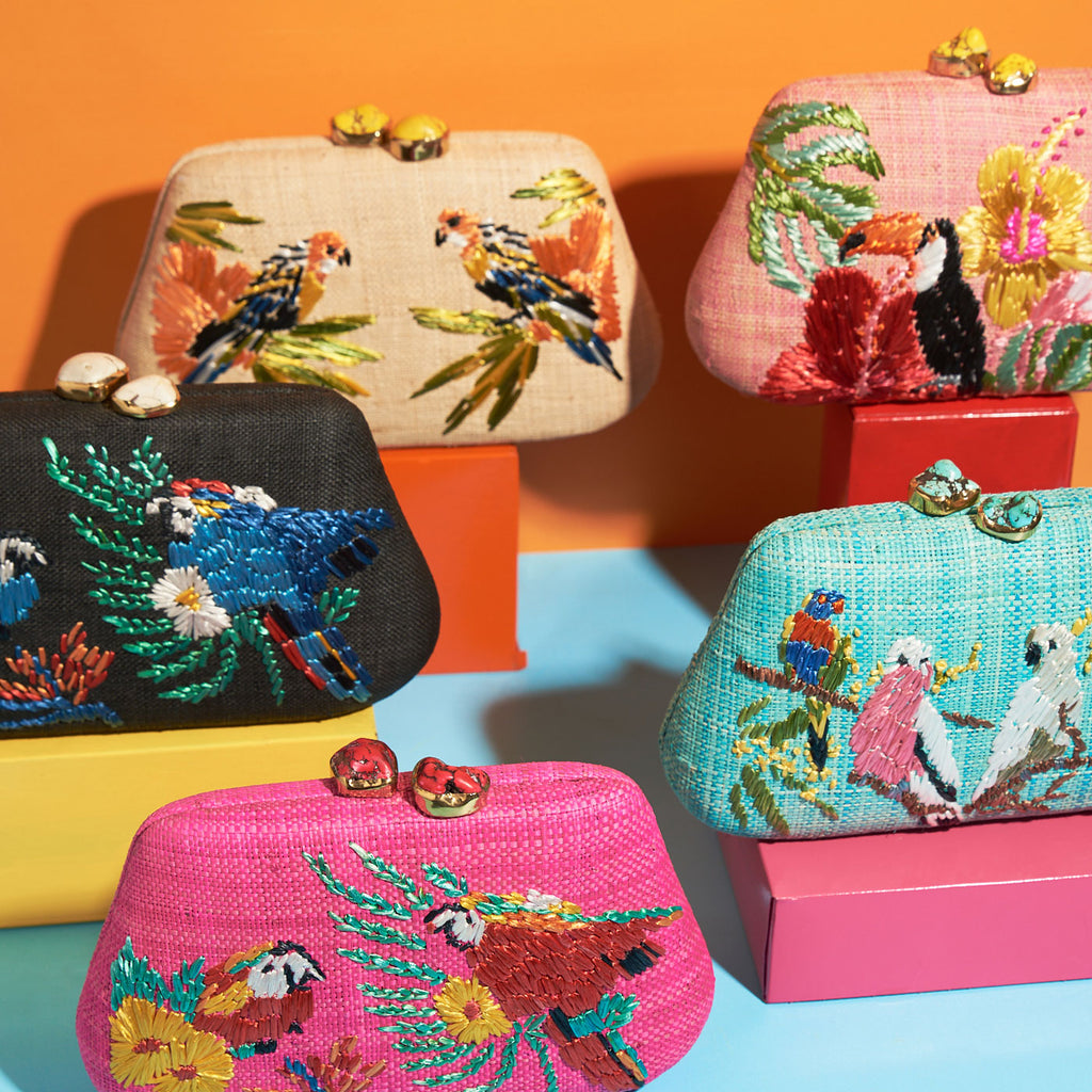 Wicker Darling light pink tropicana clutch purse toucan bag flamingo bag sits on a colourful background
