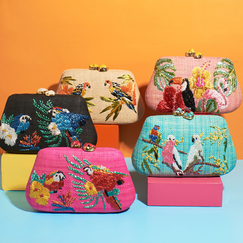 Wicker darling natural fabric clutch with embroidered tropical birds sits on a colourful background