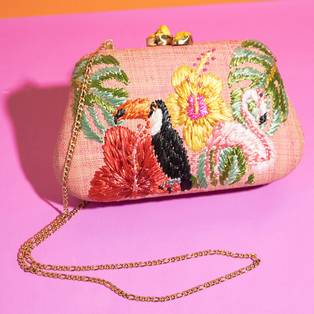 Wicker Darling light pink tropicana clutch purse toucan bag flamingo bag sits on a colourful background