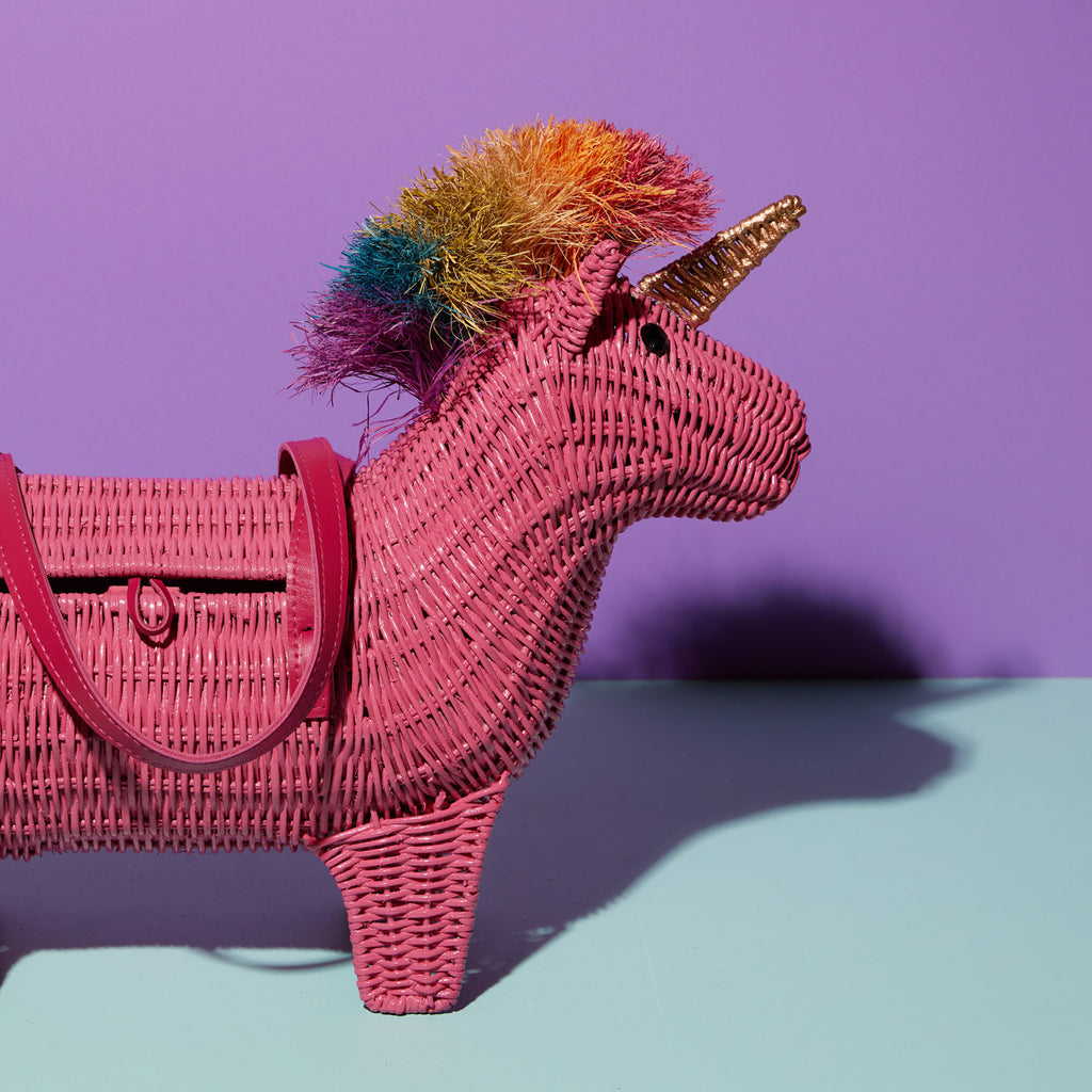 Viola the pink unicorn bag has a rainbow mane and sits in a colourful background