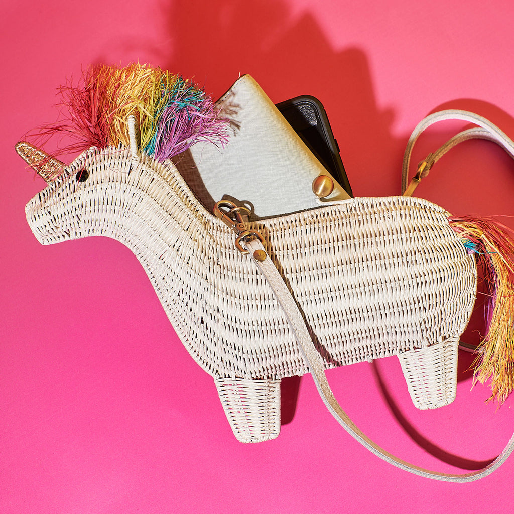 Wicker Darling victoria rainbow unicorn shaped clutch hanging in a colourful room