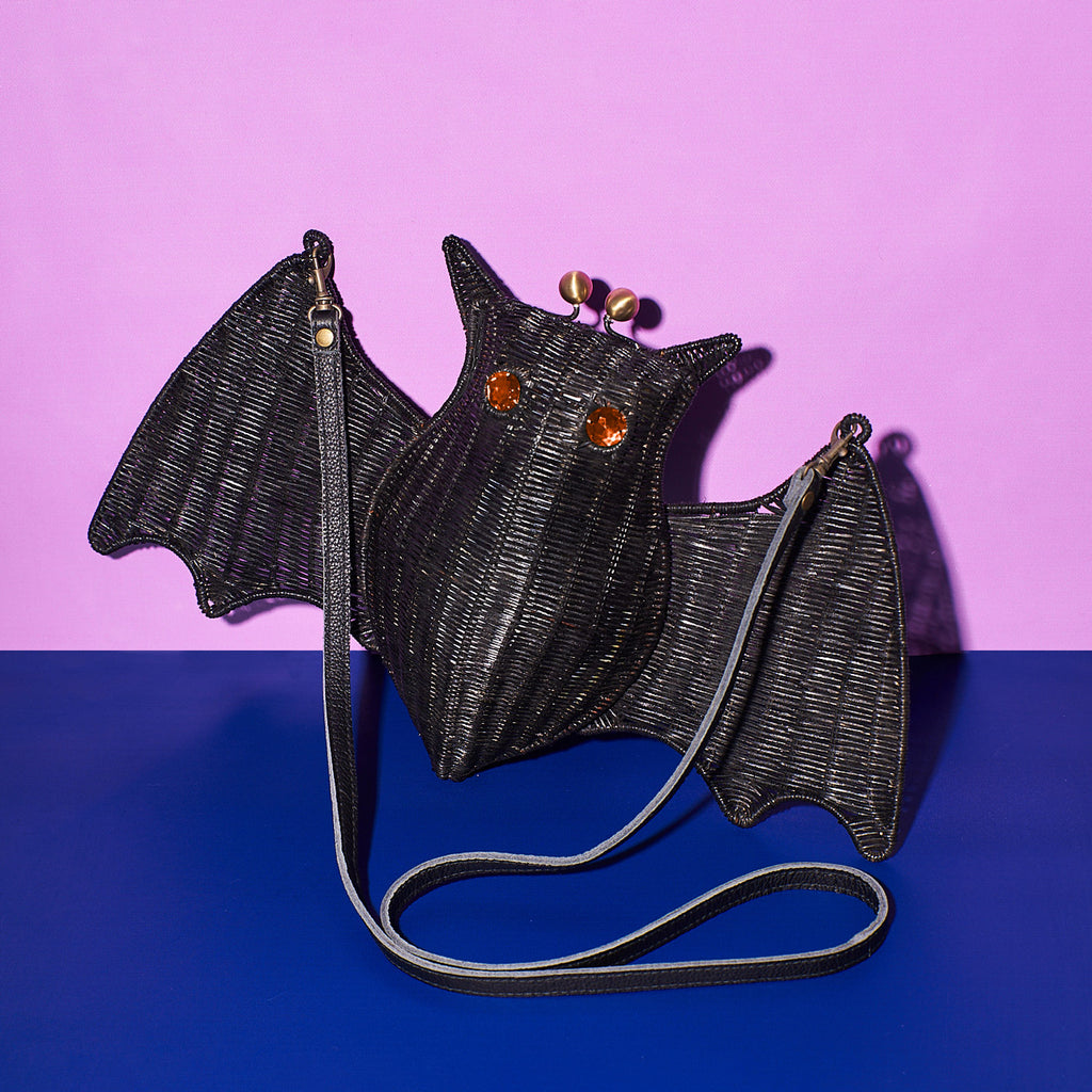 Elizabath Bathory the bat shaped purse bat handbag sits in a colourful background