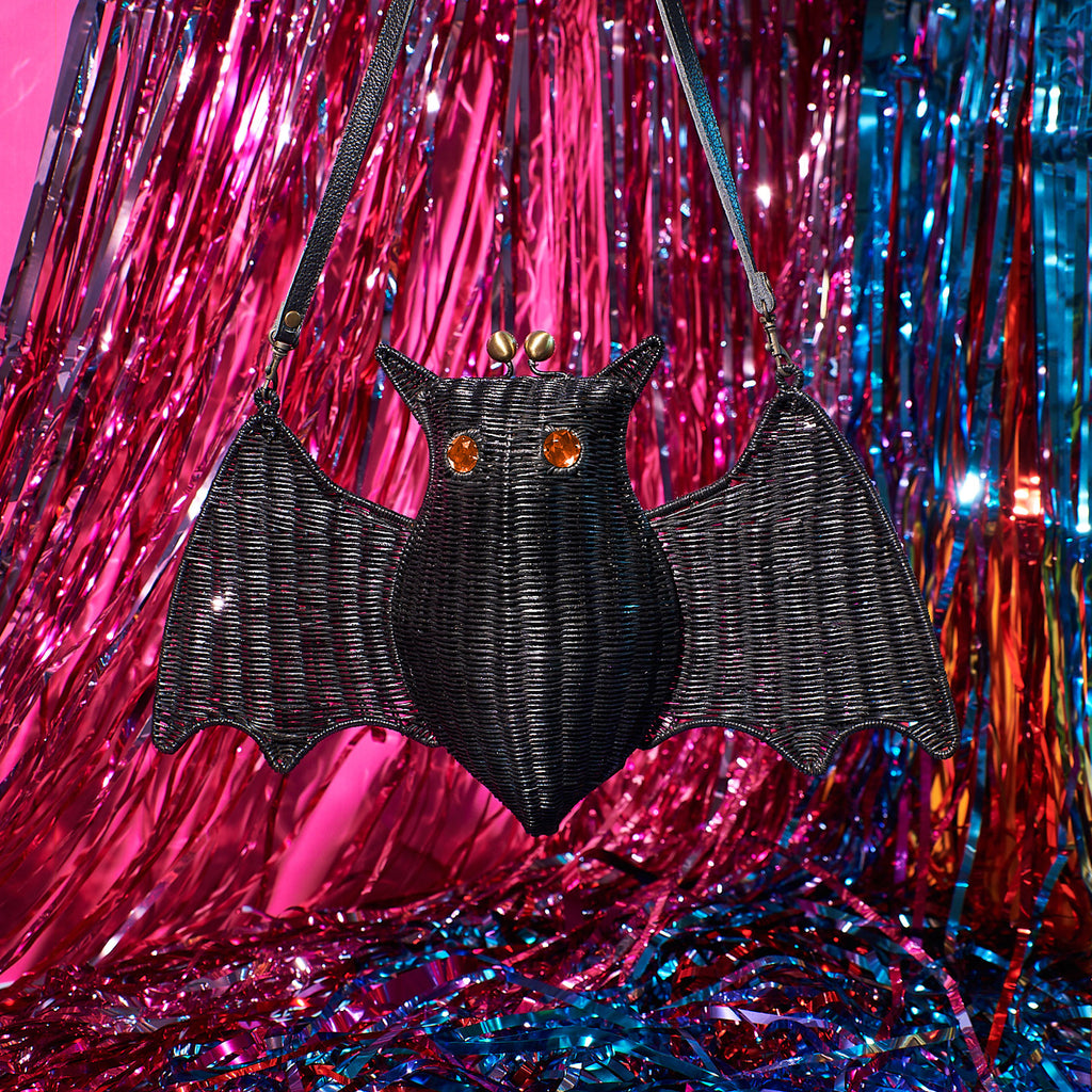 Elizabath Bathory the bat shaped purse bat handbag sits in a colourful background