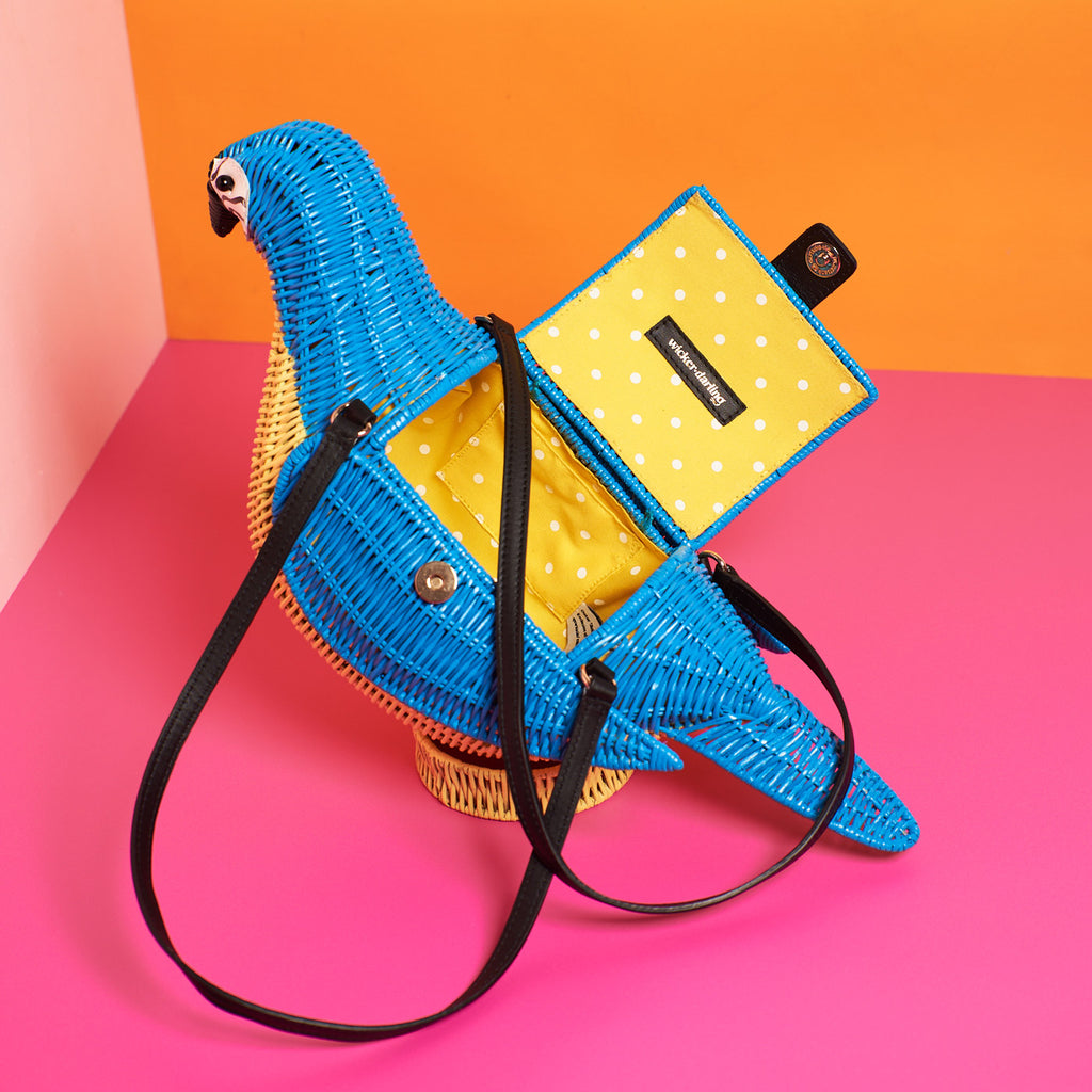 Wicker Darling blue macaw bag macaw purse sits in a colourful background