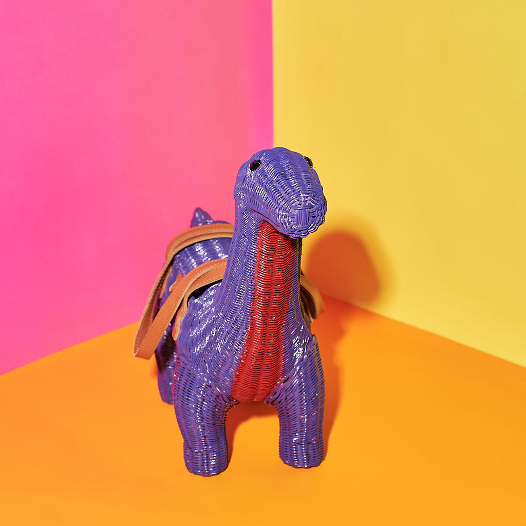 Wicker Darling emily brontesaurus cute purple dinosaur purse sits in a colourful room