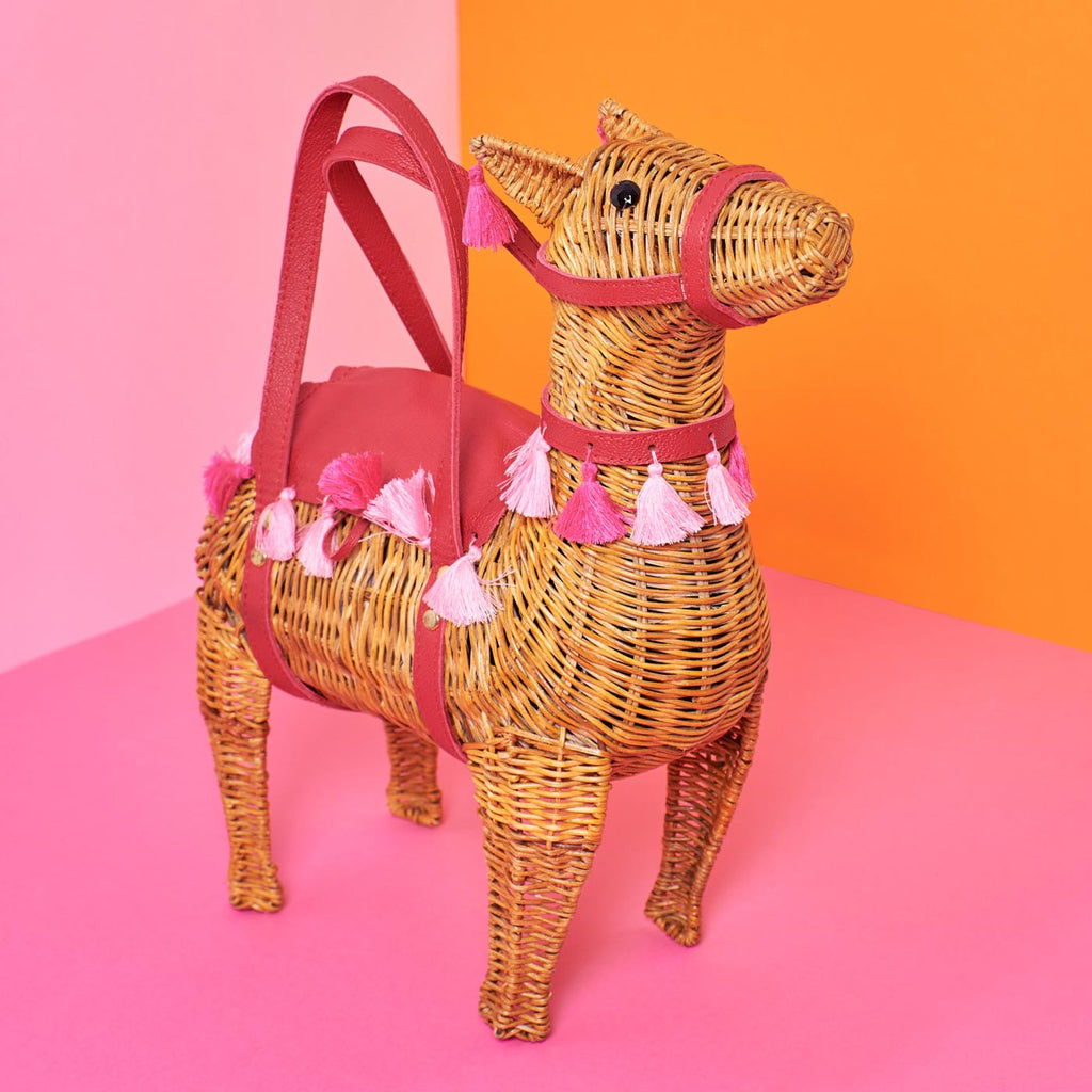 Wicker Darling lola llama purse llama shaped bag sits in a colourful background