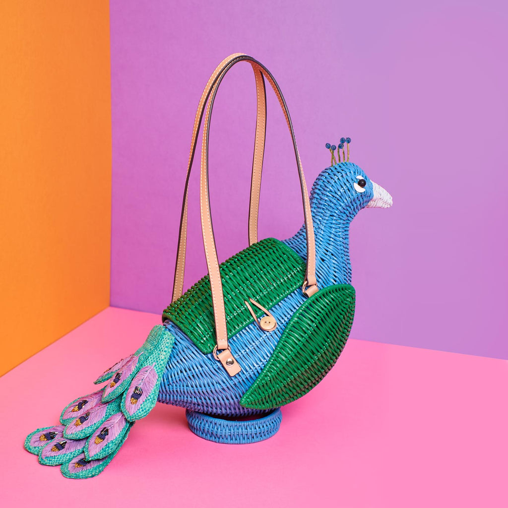 Wicker Darling percy peacock purse peacock tail bag sits in a colourful room