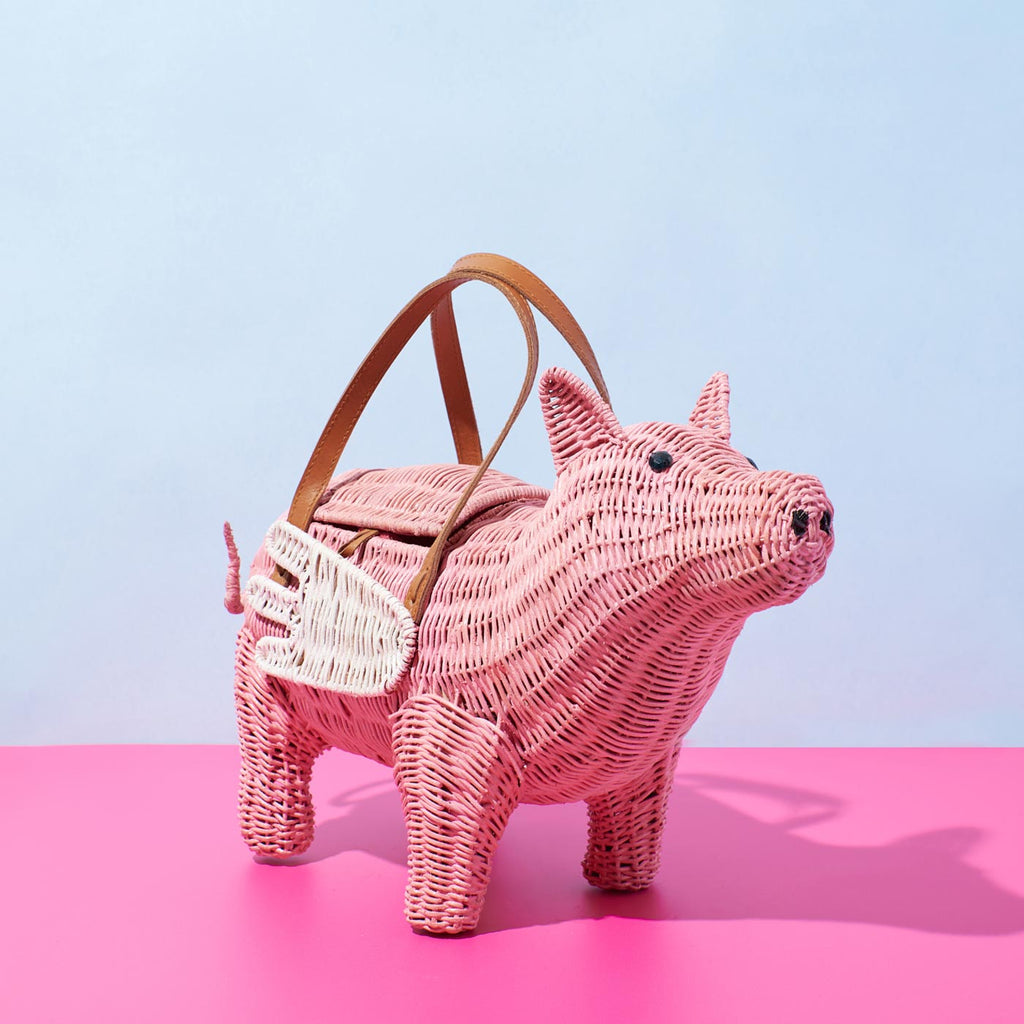 Wicker Darling pigasus pig purse flying pig handbag sits in a colourful background