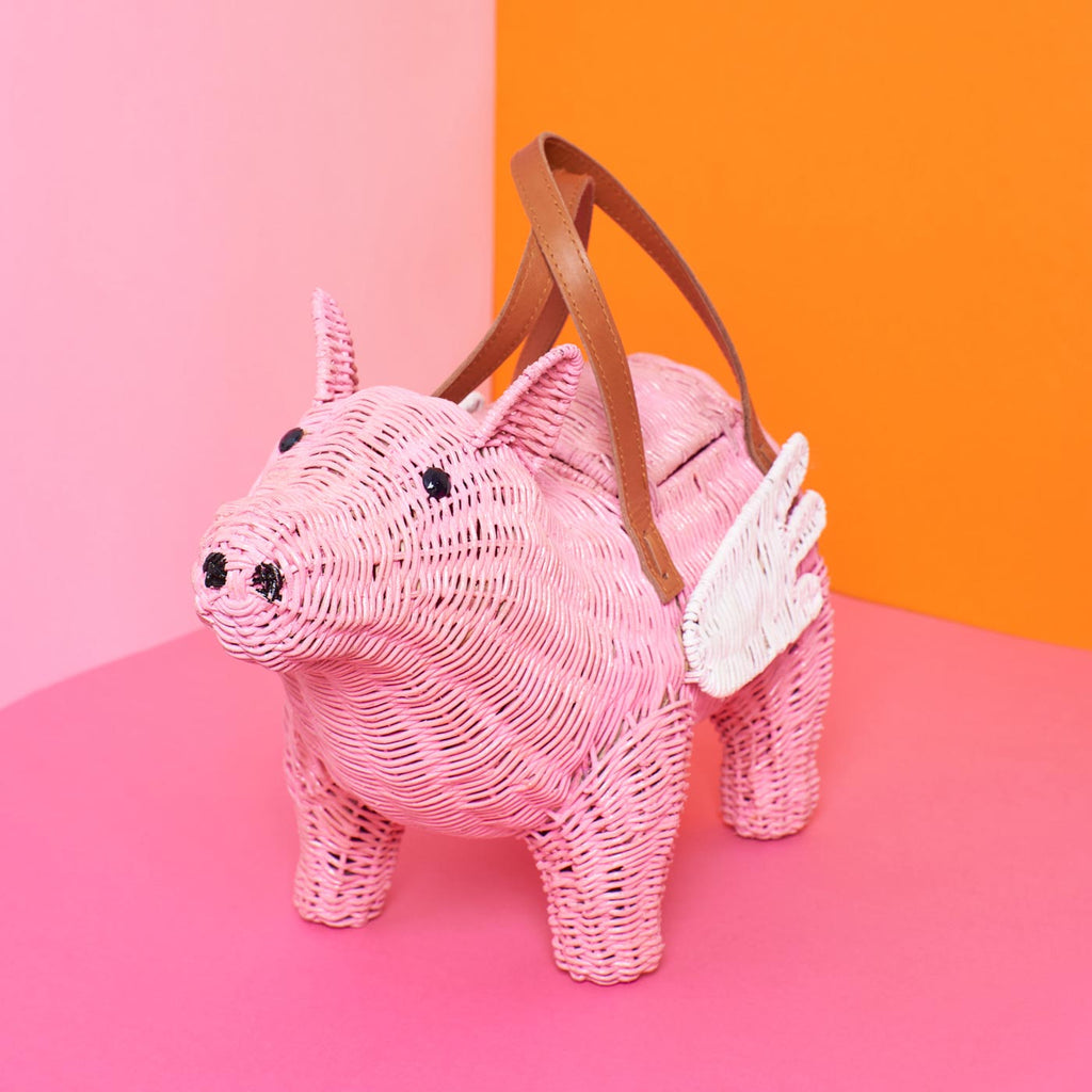 Wicker Darling pigasus pig purse flying pig handbag sits in a colourful background
