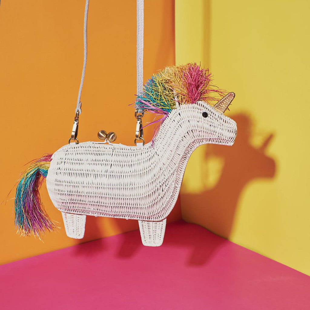 Wicker Darling victoria rainbow unicorn shaped clutch hanging in a colourful room