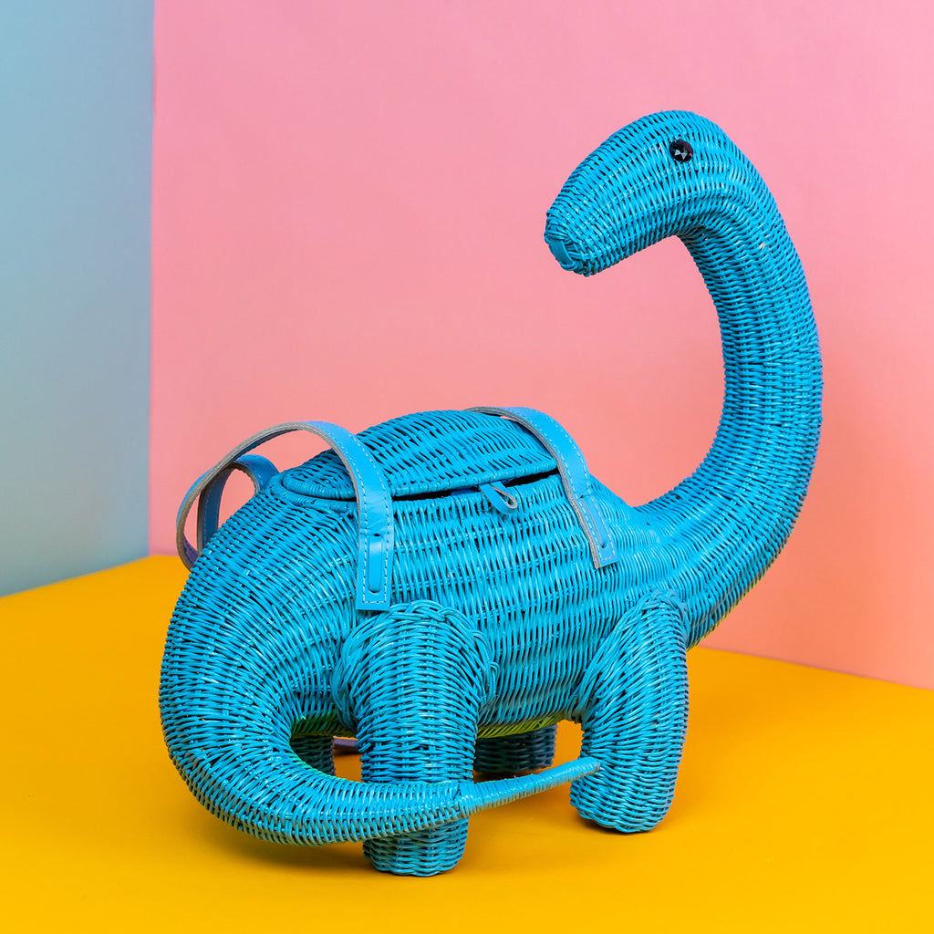 Wicker Darling blue brontesaurus purse dinosaur shaped bag sits in a colourful background