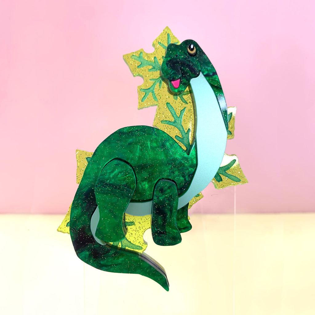 Wicker Darling What Willow Did collab dinosaur brooch sits in a colourful background