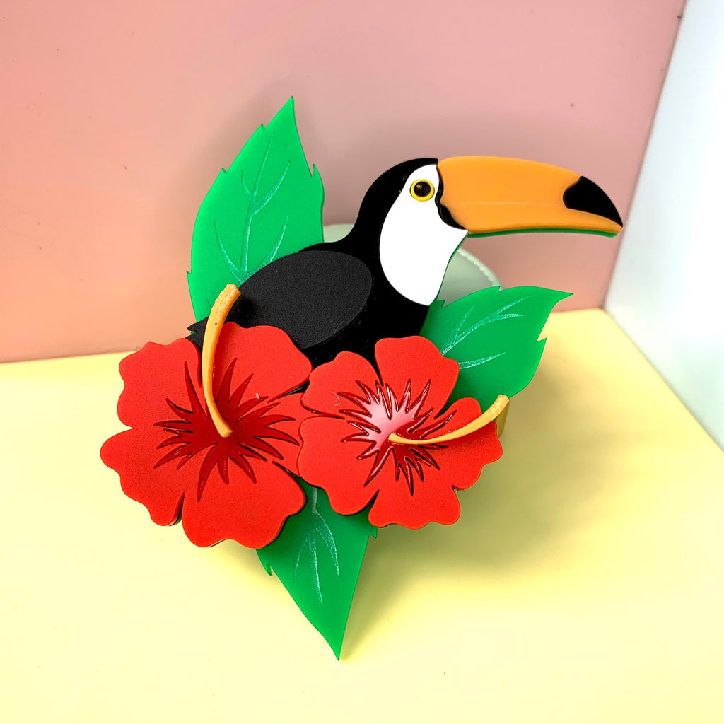Wicker Darling What Willow Did collab toucan brooch sits in a colourful background